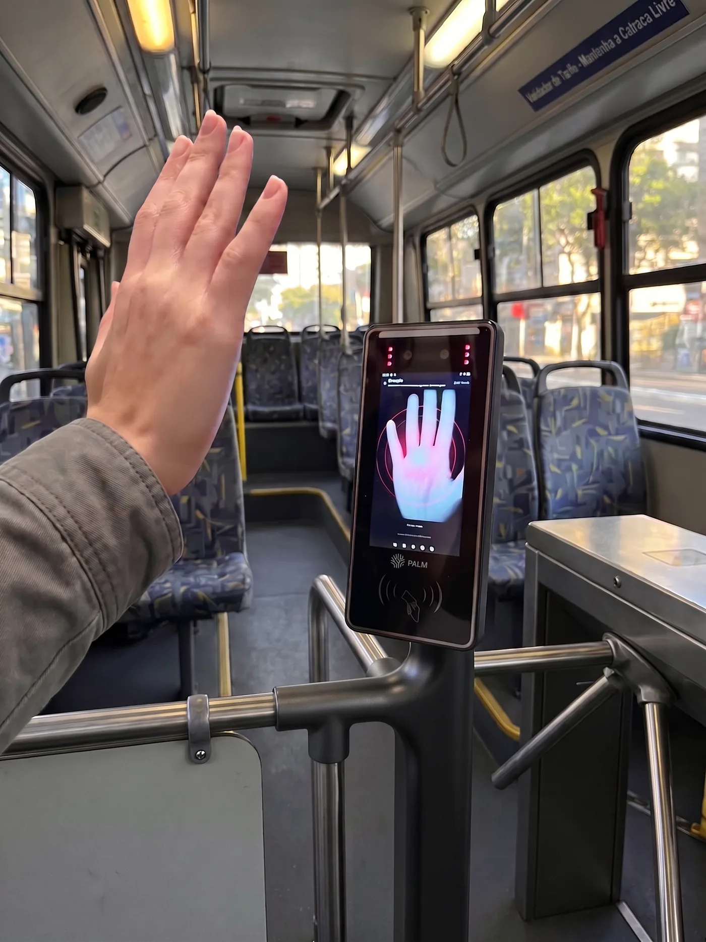 Validador Palm instalado junto à catraca de um ônibus urbano, com passageiro aproximando a mão